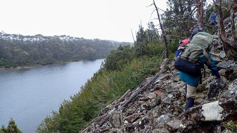 hiker on rocks traverses lake ball tasmania