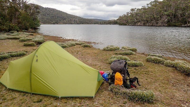 green tent and backpack beside Lake Ball in Tasmania