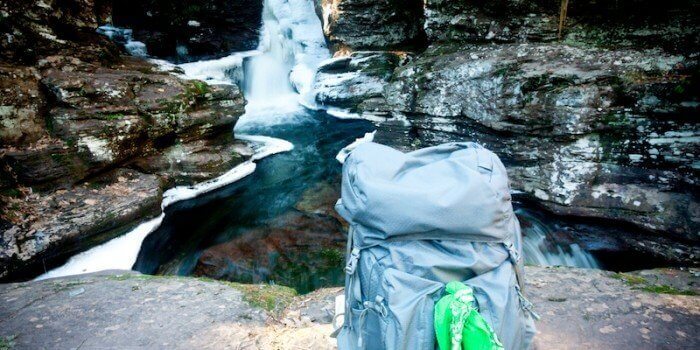 Backpacking sitting on rocks by a waterfall
